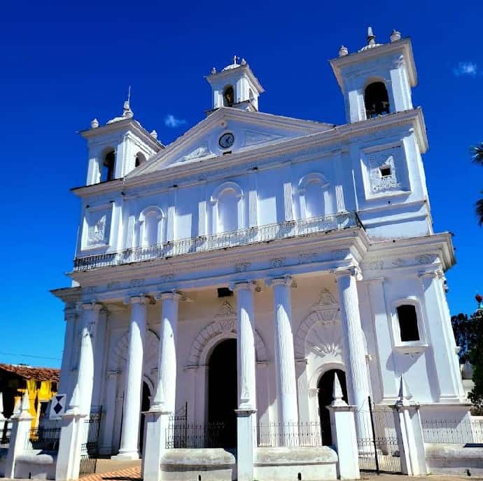 Historic colonial church in Suchitoto, El Salvador with white facade and twin bell towers.