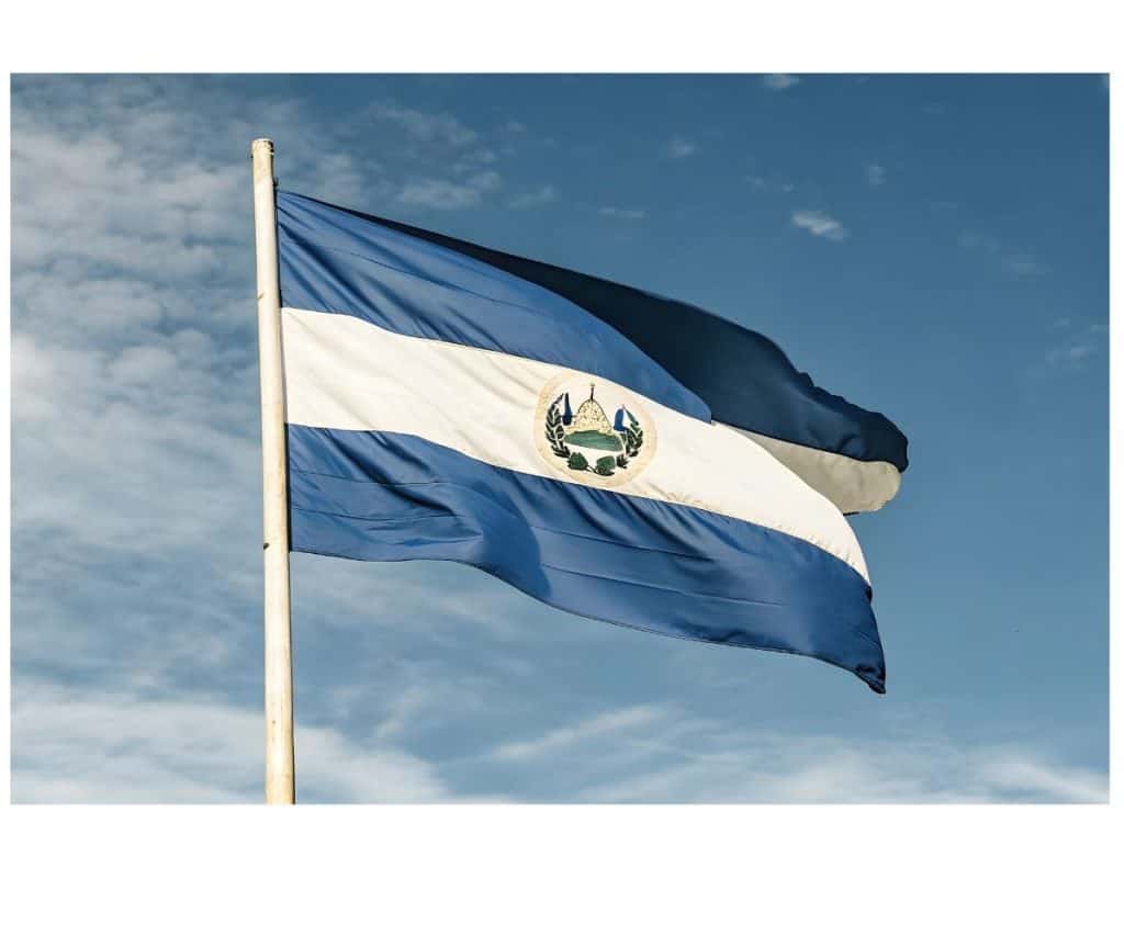 El Salvador flag flying high with vibrant blue and white stripes and national emblem.