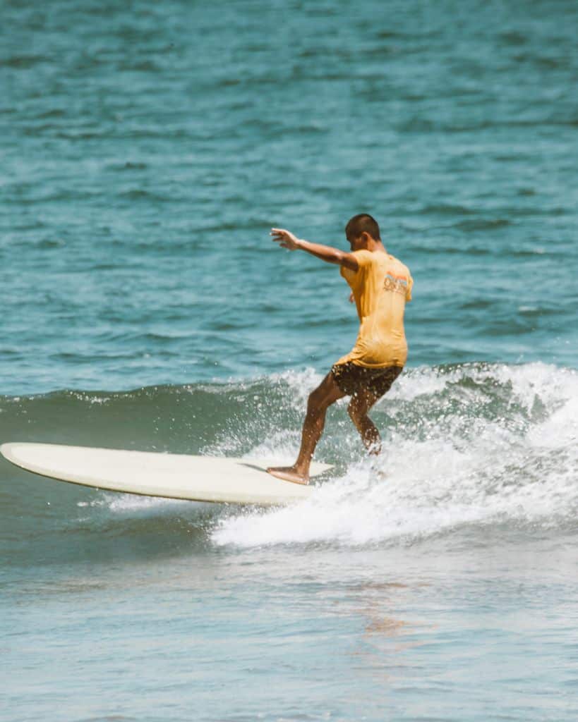 Beginner surfer riding whitewater wave at Playa El Tunco, El Salvador
